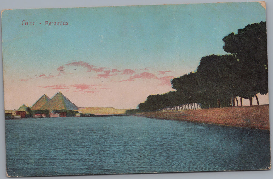 Giza — Distant Pyramids across Water and Tree-Lined Bank